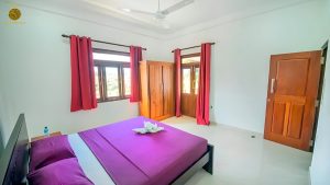 Villa Noble Horizon Sri Lanka interior – double guestroom with balcony access, wooden wardrobe and large windows with red curtains