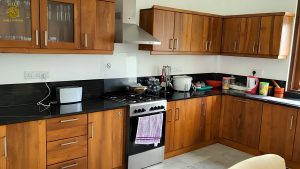 Villa Noble Horizon Sri Lanka interior – modern kitchen with wooden cabinets, black countertop, gas stove and cooking utensils