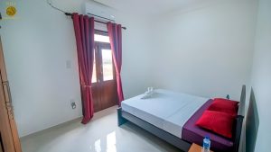 Villa Noble Horizon Sri Lanka interior – single guestroom with balcony access, double bed, red pillows and natural light