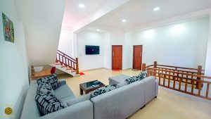 Villa Noble Horizon Sri Lanka interior – upstairs guest lounge with corner sofa, TV, desk and wooden staircase